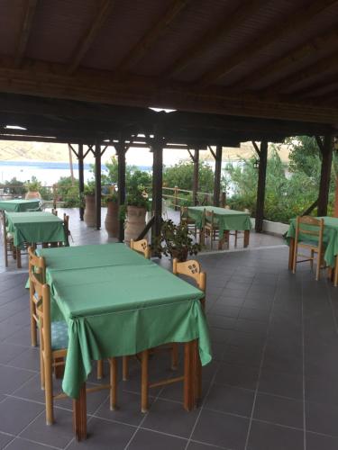 a covered patio with green tables and chairs at House Anastasia in Agios Georgios Pagon