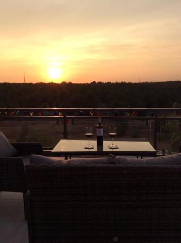 two glasses of wine sitting on a table with the sunset at Paradise Terrace House in Quinta do Conde