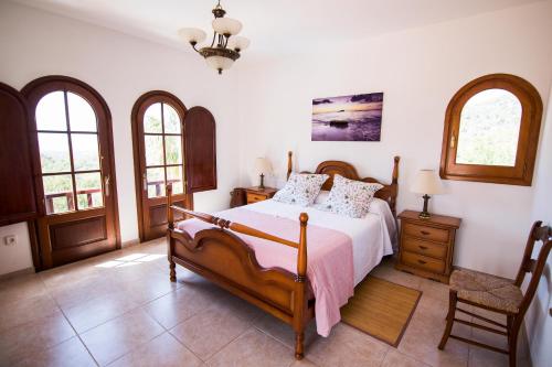 a bedroom with a bed and two windows at Villa Ca na Vinya in Cala Tarida