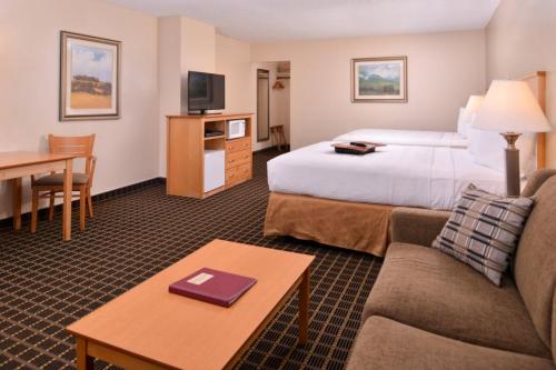 a hotel room with a bed and a couch and a table at Campus Inn & Suites Eugene Downtown in Eugene