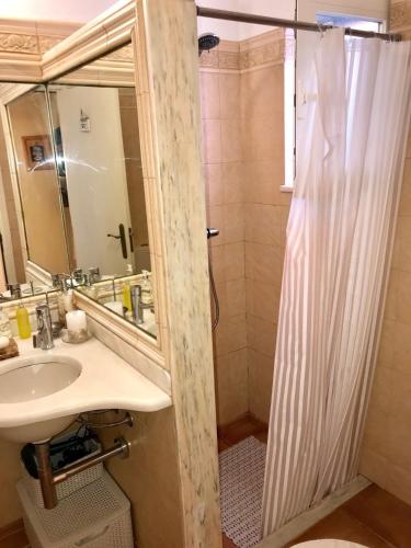 a bathroom with a sink and a shower with a mirror at Casa Mestre André in Benagil