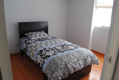 1 dormitorio con 1 cama con edredón blanco y negro en Beachfront Condo San Miguel, en Lima