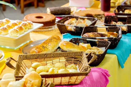a table topped with baskets of bread and pastries at Itapetinga Hotel in Atibaia
