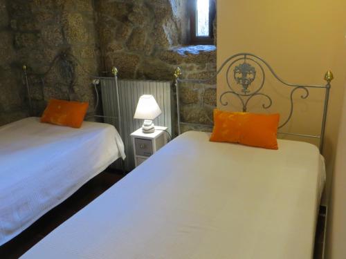 two beds with orange pillows in a room at Casa de Fujacos in Valença