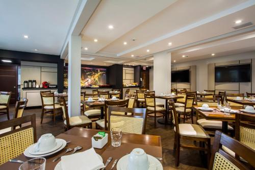 un restaurante con mesas y sillas y un bar en Santa Inn Hotel, en Balneário Camboriú