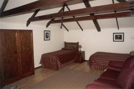 a bedroom with two beds and a chair in a room at Royal Coachman in Clarens