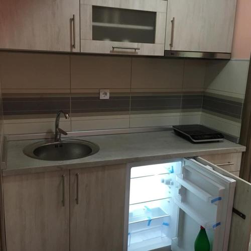 a kitchen with a sink and an open refrigerator at Apartmani Kristina & Kriss in Užice