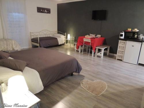 a bedroom with two beds and a table and a kitchen at La Casa del Colonnello in Vercelli