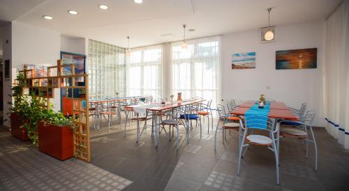 a dining room with tables and chairs and windows at Hostel Soline in Portorož