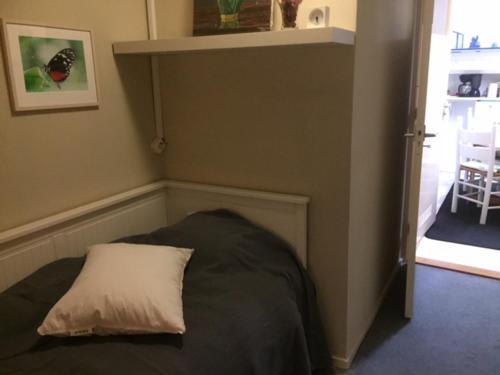 una camera da letto con un letto con un cuscino bianco sopra di Gezellige zolder in Wassenaar met dakterras a Wassenaar