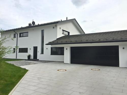 a white house with a large garage at Ferienwohnung Black White in Raubling