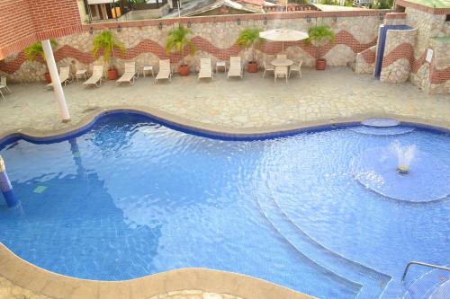 a large blue swimming pool with chairs and umbrellas at Hotel Villa Playa Grande in Playa Grande