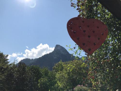 a heart hanging from a tree with a mountain in the background at Ferienwohnungen im Lüftlmalereck, Mussldomahaus in Oberammergau