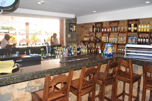 a bar with wooden chairs and a counter with alcohol at Hotel Villa Playa Grande in Playa Grande