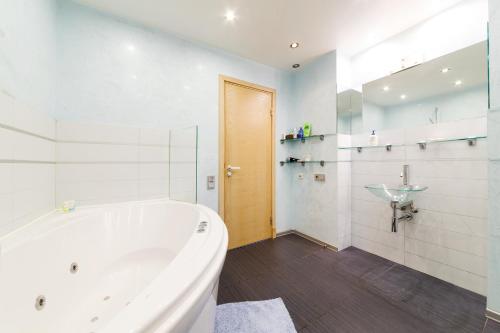 a white bathroom with a tub and a sink at Brivibas LUX in Riga