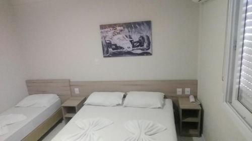 a bedroom with two beds and a picture on the wall at Hotel Ville House Premium in Canoas