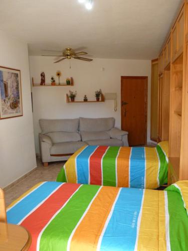 2 łóżka w pokoju z kanapą w obiekcie NEW centro Torremolinos w mieście Torremolinos