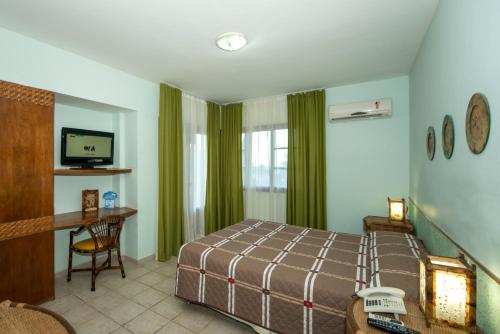 a bedroom with a bed and a desk and a television at Divi-Divi Praia Hotel in Natal