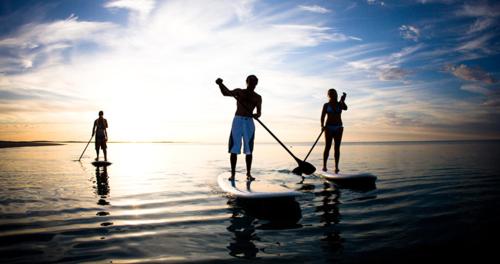 Tres personas están de pie en una tabla de surf en el agua en CASA DE CAMPO PATRIMÔNIO en Brotas