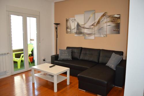 a living room with a black couch and a table at Apartamento La Paz in Logroño