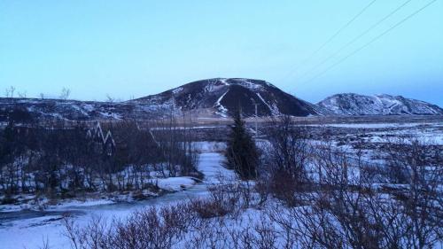 a mountain in the middle of a snow covered field at Þingvellir Golden Circle Cottage in Veiðilundur