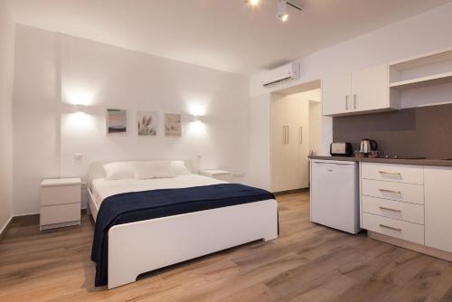 a white bedroom with a bed and a kitchen at The Jolo in Limassol