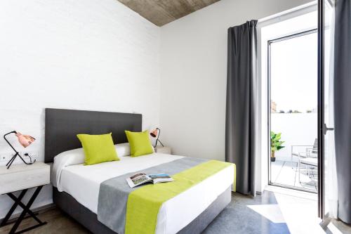 a bedroom with a bed with yellow and gray pillows at La Puerta de Palacio - Adults Only in Seville