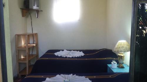 a room with two beds and a table with a lamp at Hospedaje Eli Panajachel in Panajachel