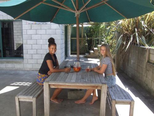 two women sitting at a picnic table under an umbrella at Anakiwa Lodge in Anakiwa
