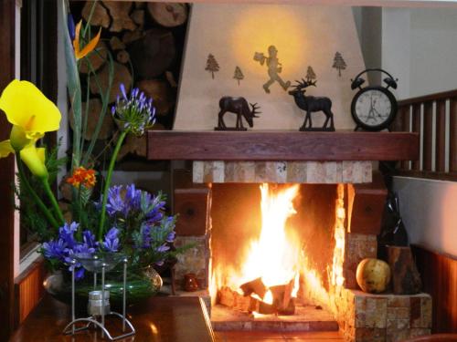 a fireplace in a room with a clock and flowers at Hotel el Leñador in Mazamitla