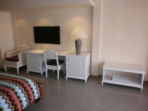 Habitación con escritorio, TV y sillas. en Studio en bord de mer - Résidence La Vieille Tour, en Le Gosier