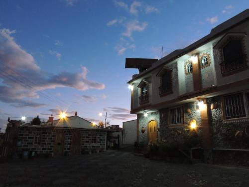 a house with lights on the side of it at night at Hostal Ñuca Huasi in Tambillo