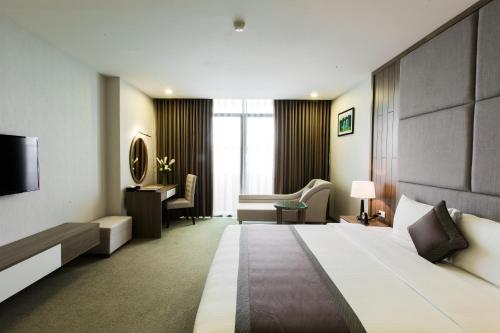 a hotel room with a large bed and a desk at Muong Thanh Luxury Ha Nam in Phủ Lý