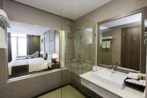 a bathroom with a sink and a bed and a mirror at Muong Thanh Luxury Ha Nam in Phủ Lý