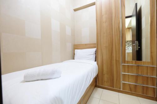 a small bedroom with a bed and a glass door at Minimalist 2BR Serpong Greenview Apartment By Travelio in Serpong