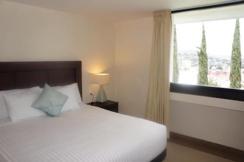 a bedroom with a white bed and a window at Hotel Mirante Tlaxcala in Tlaxcala de Xicohténcatl