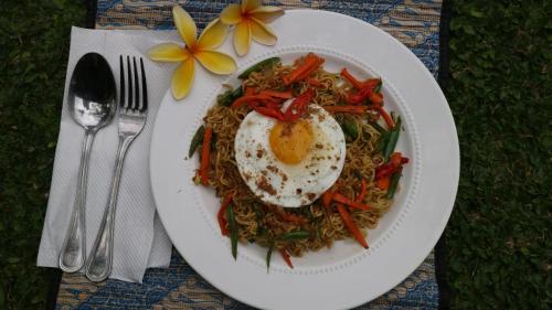 een bord eten met een ei op de noedels bij Villa Alam Biru Gardenia in Seminyak
