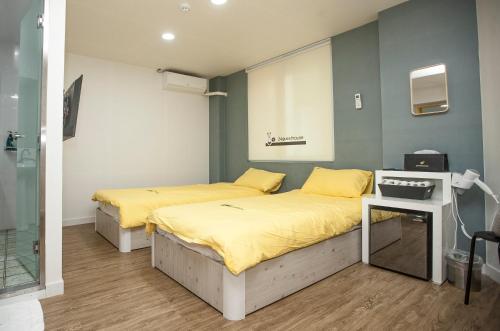 two beds in a room with yellow sheets at 24 Guesthouse Jeonju in Jeonju