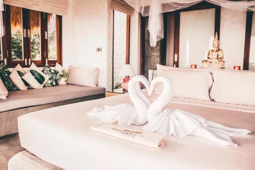 two white swans sitting on a table in a bedroom at Langkhai Garden in Koh Tao
