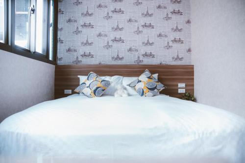 a bedroom with a large bed with white sheets and pillows at Meng Yun Ge Hotel in Jiaoxi