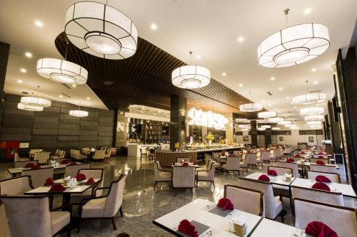 a restaurant with tables and chairs and chandeliers at Muong Thanh Luxury Ha Nam in Phủ Lý