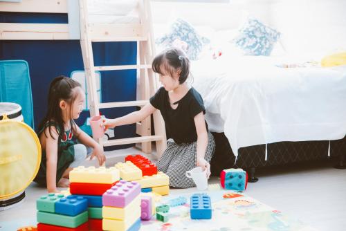 two young girls playing with blocks in a bedroom at Meng Yun Ge Hotel in Jiaoxi