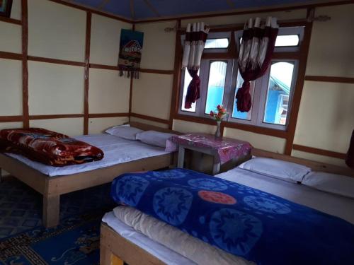 a room with two beds and two windows at Vamoose Arjastik Homestay in Pedong
