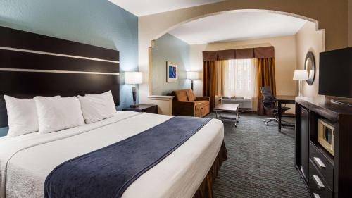 Habitación de hotel con cama grande y sala de estar. en Best Western Plus Northwest Inn and Suites Houston, en Houston