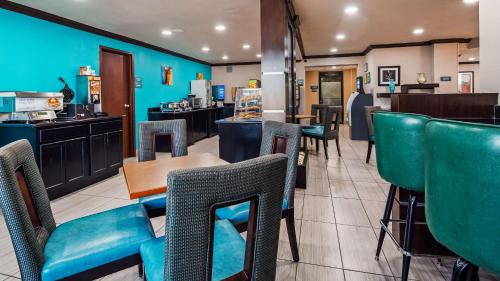 a restaurant with blue walls and green chairs at Best Western Webster Hotel, NASA in Webster
