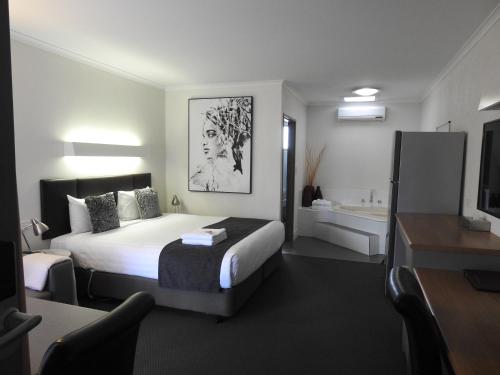a hotel room with a bed and a bathroom at Wine Village Motor Inn in Rutherglen