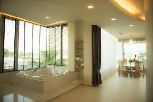 a large bathroom with a tub and a dining room at The Beverly Hills Hotel in Nakhon Ratchasima