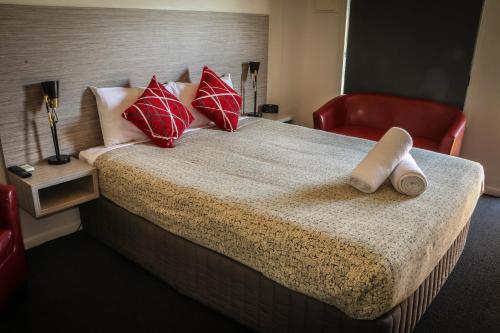 ein Hotelzimmer mit einem Bett mit roten Kissen in der Unterkunft Emerald Park Motel in Emerald