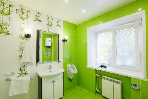 a green bathroom with a sink and a mirror at Apartments Petrovskie on Kirova 39A in Tomsk