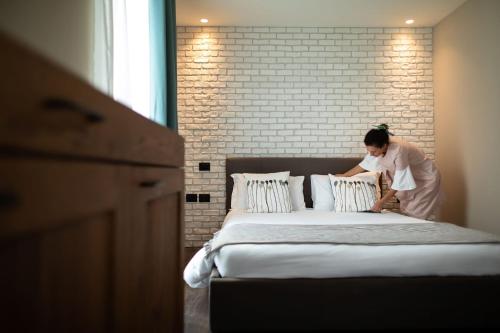 a woman is putting pillows on a bed at Hotel Locanda Al Piave ***S in San Donà di Piave